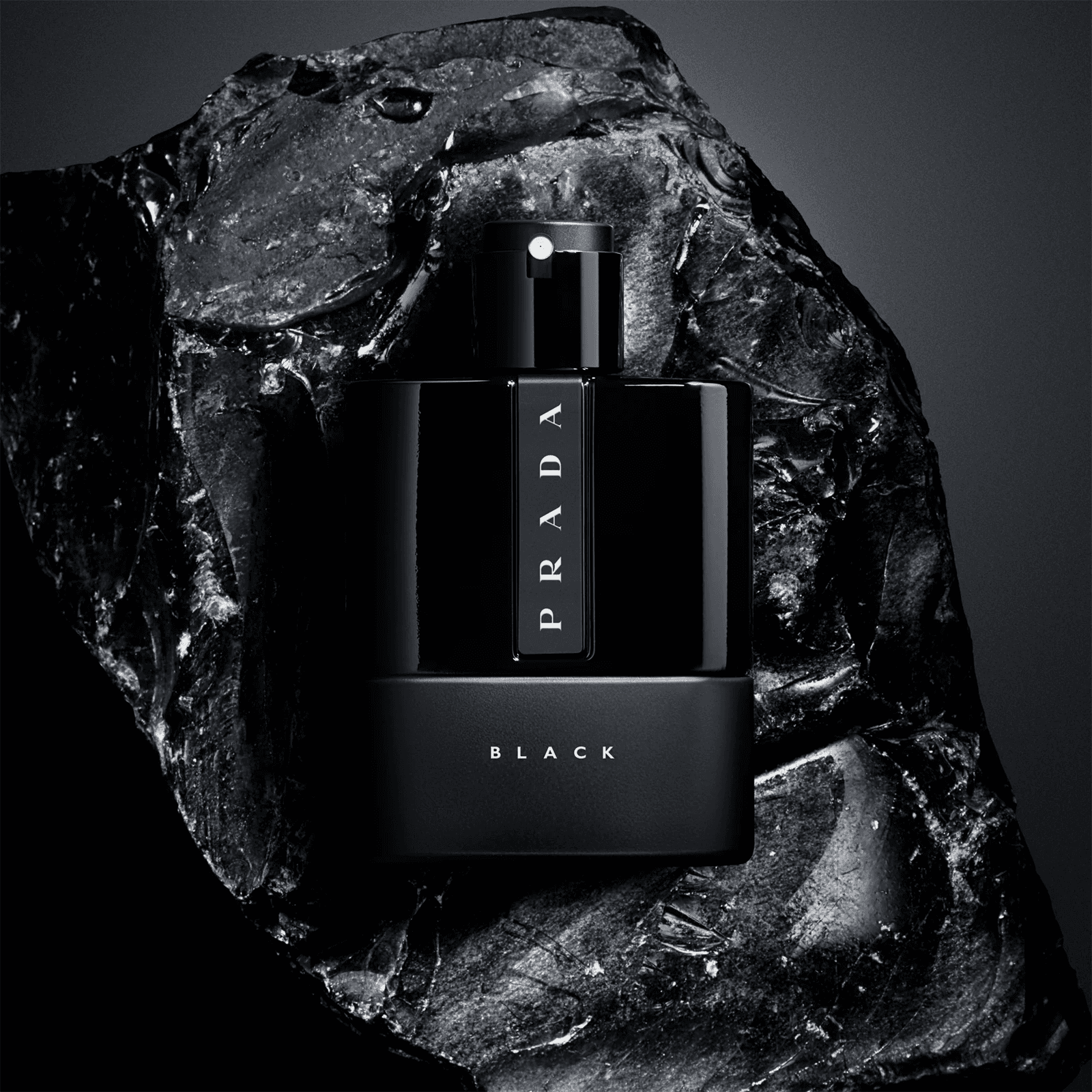Black fragrance bottle on dark mineral stone